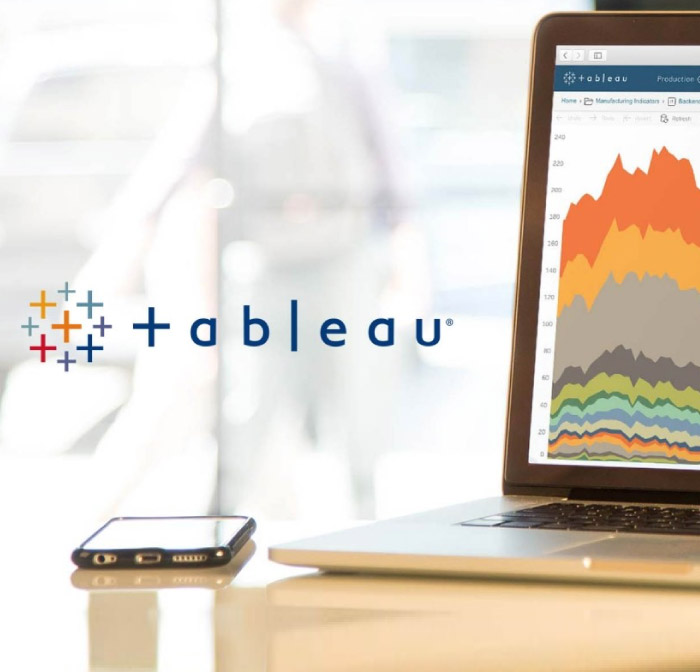 escritorio con celular y computador más el logo de tableau al medio